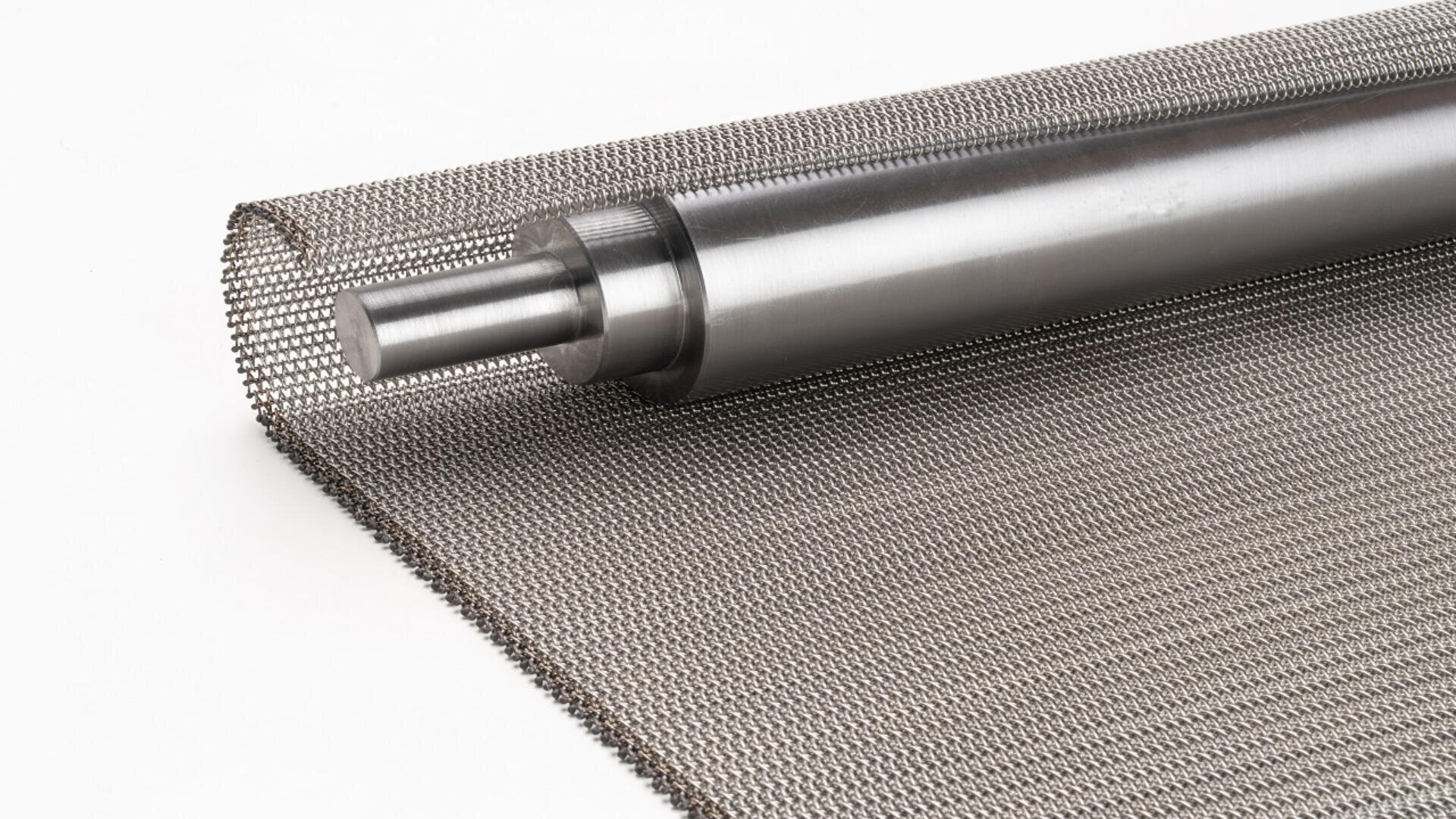 A roll of fine metal wire mesh with a cylindrical metal rod placed on top, partially unrolled on a white background.