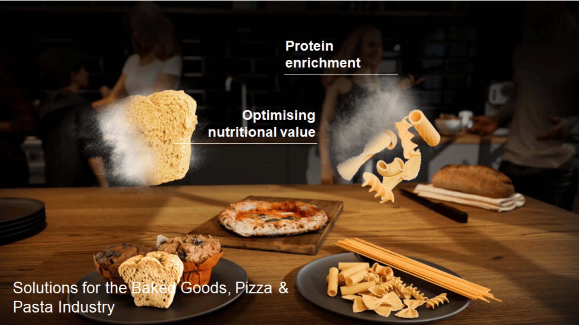 A wooden table displays muffins, pizza, bread, and various pasta. Floating text reads “Protein enrichment” and “Optimising nutritional value” above stylized pasta and bread imagery. Caption: “Solutions for the Baked Goods, Pizza & Pasta Industry.”.
