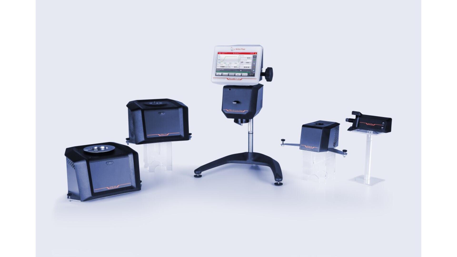 Ein Laborgerät mit digitaler Anzeige auf einem Ständer ist von vier schwarzen, kastenförmigen Zubehörteilen unterschiedlicher Größe umgeben, die alle vor einem hellen Hintergrund stehen.