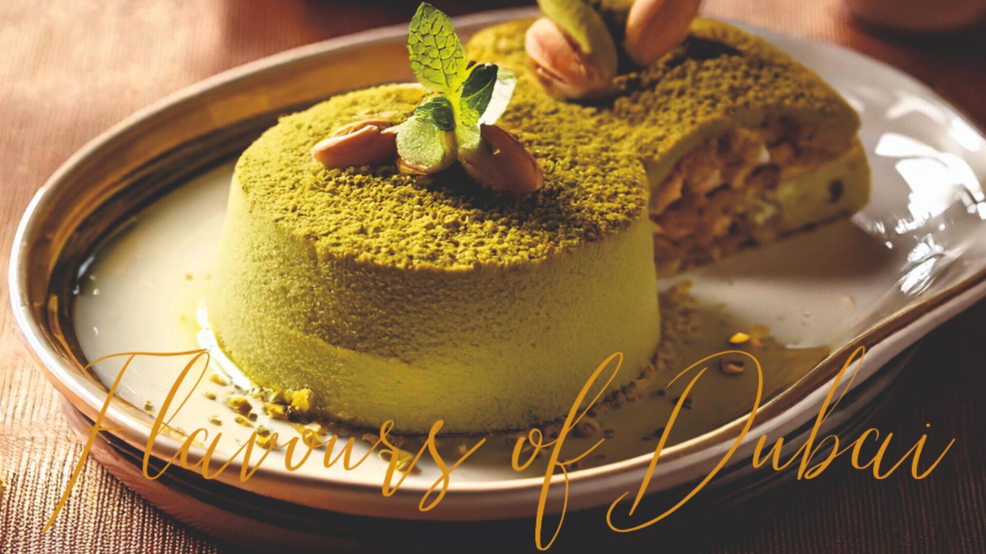 A pistachio dessert garnished with mint leaves and nuts sits on a plate, with “Flavours of Dubai” written in elegant script across the image.