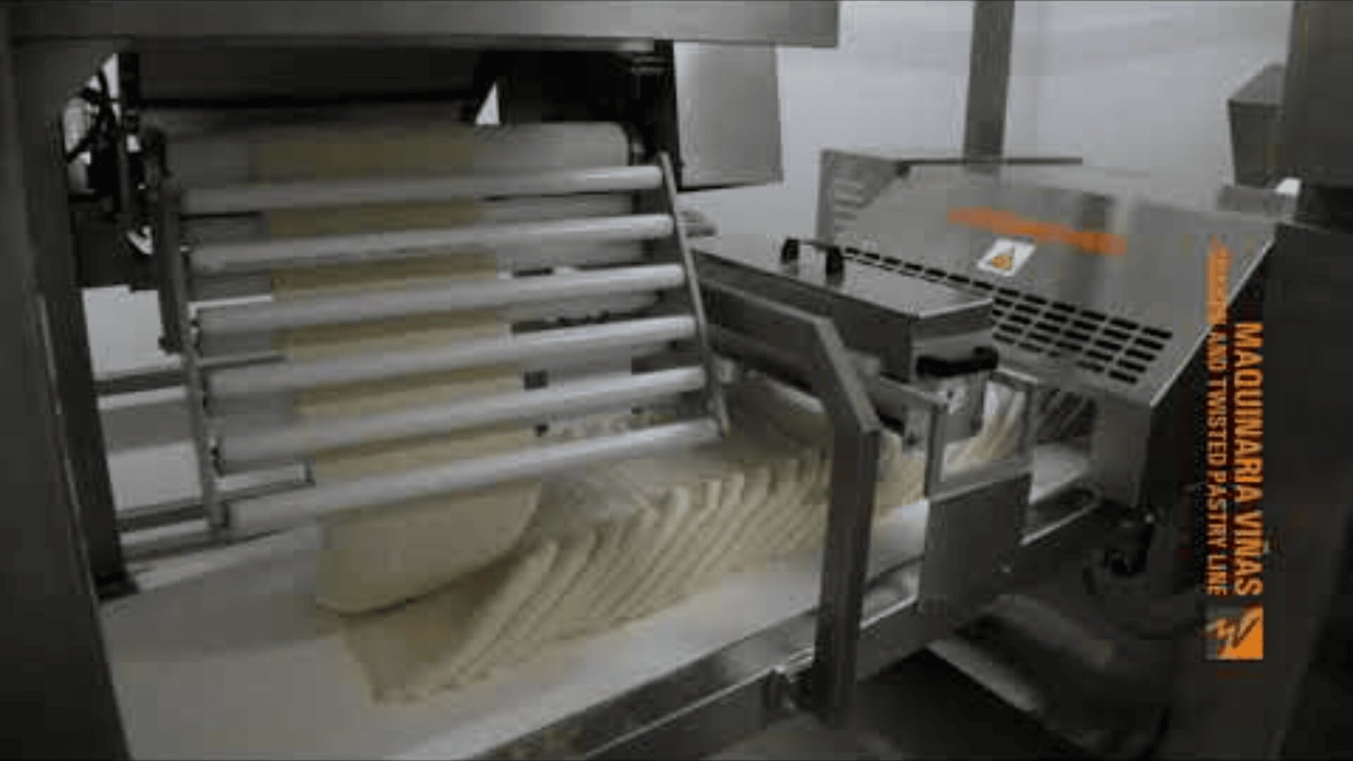 A standard dough sheeter processes and flattens the dough into even, thin sheets, stacking the finished dough pieces neatly under the rollers.