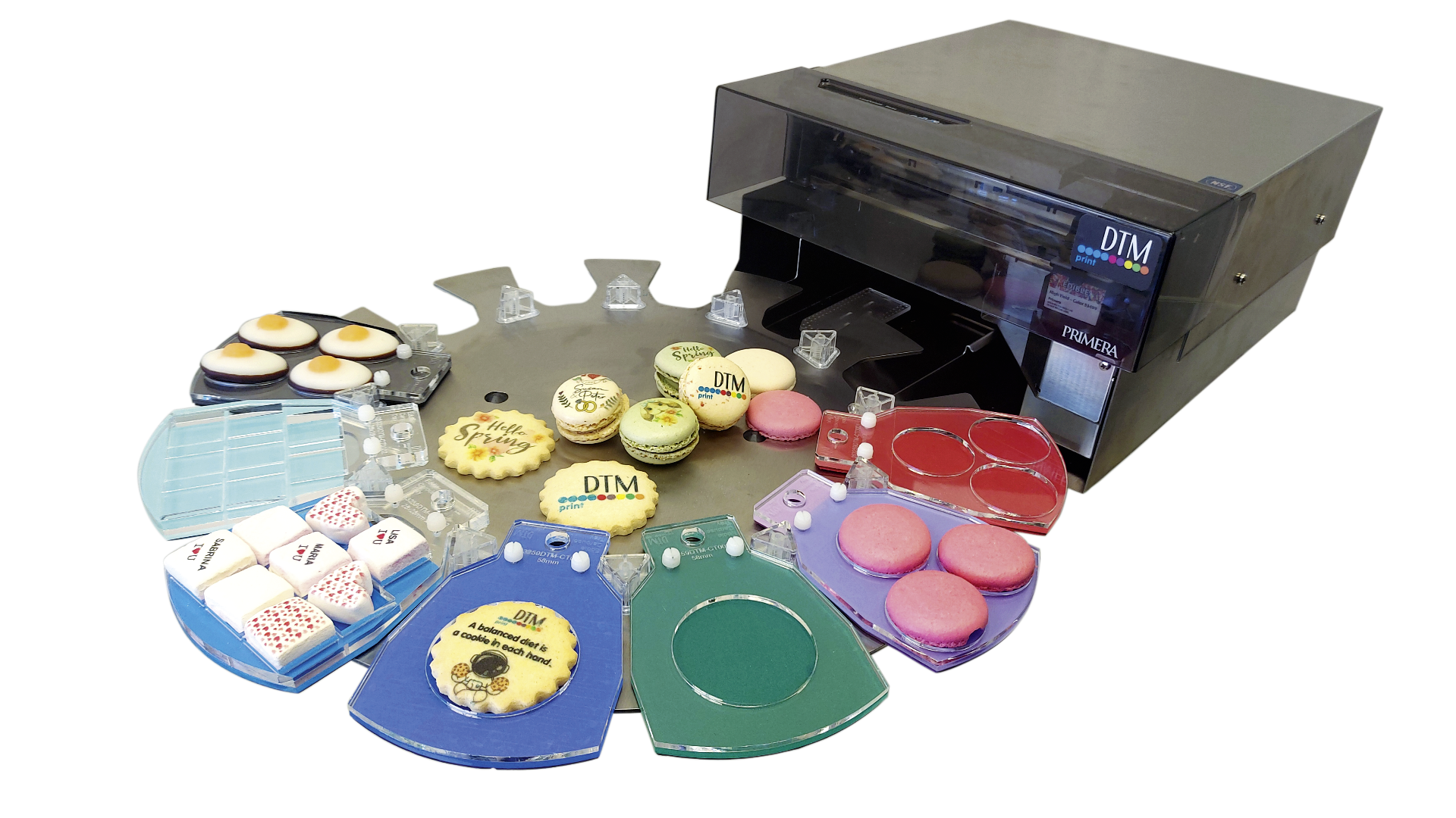 Ein Lebensmitteldrucker mit bedruckten Keksen, Macarons und Fondant-Leckereien, die um ihn herum angeordnet sind und farbenfrohe und dekorierte essbare Gegenstände zeigen, die zur individuellen Gestaltung bereitstehen.