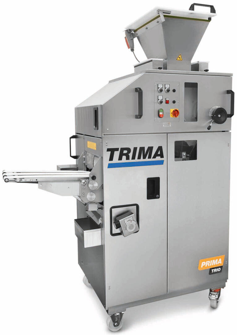 Eine große industrielle Brötchenmaschine mit der Bezeichnung TRIMA Prima Trio, mit einem Metallgehäuse, einem Bedienfeld, Förderbändern und einem oberen Trichter, alles auf Rädern montiert.