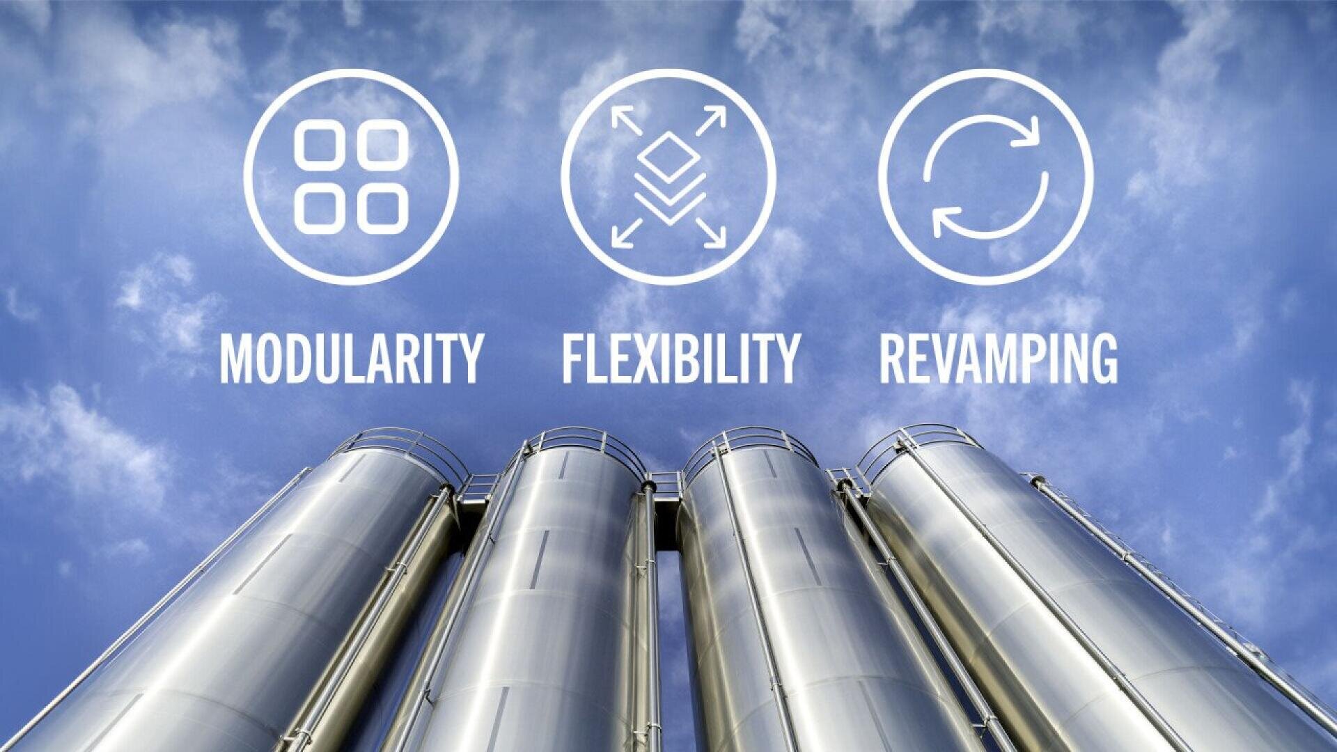 Vier hohe Metallsilos sind aus niedriger Perspektive vor einem blauen, bewölkten Himmel zu sehen. Über ihnen befinden sich Symbole und Texte mit den Worten: MODULARITÄT, FLEXIBILITÄT und MODERNE ÄNDERUNG.