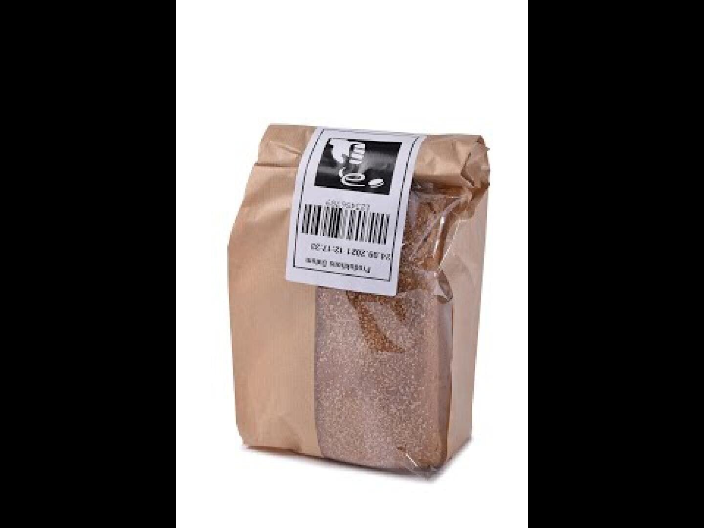 A sealed brown paper bag with a white and black label on top displaying a barcode and text, containing reddish-brown granules, likely a type of food product or spice. The bag stands upright against a white background.