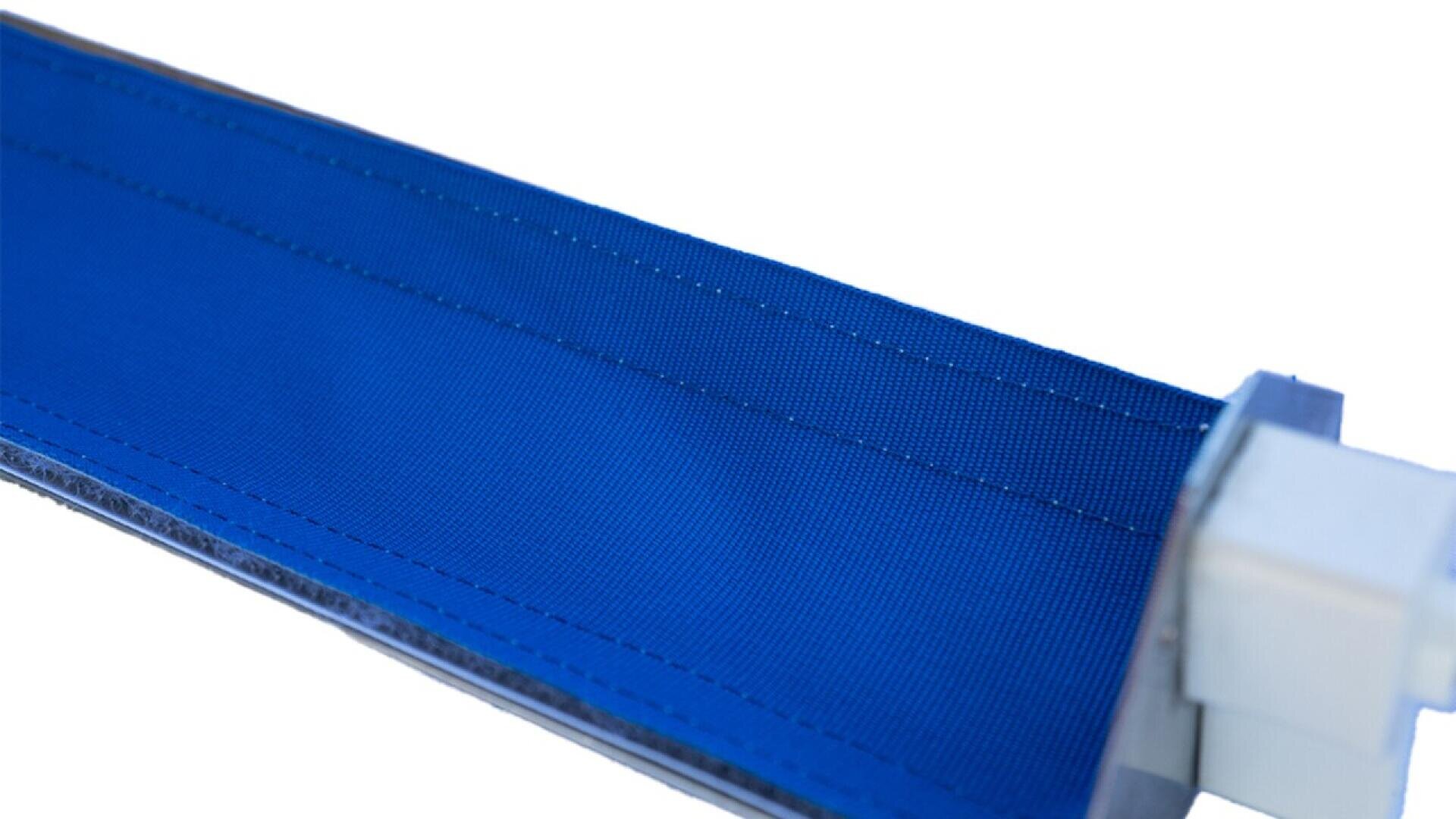 Close-up of a blue fabric conveyor belt with visible stitching along the edges, attached to a metal or plastic mechanism on the right side of the image.