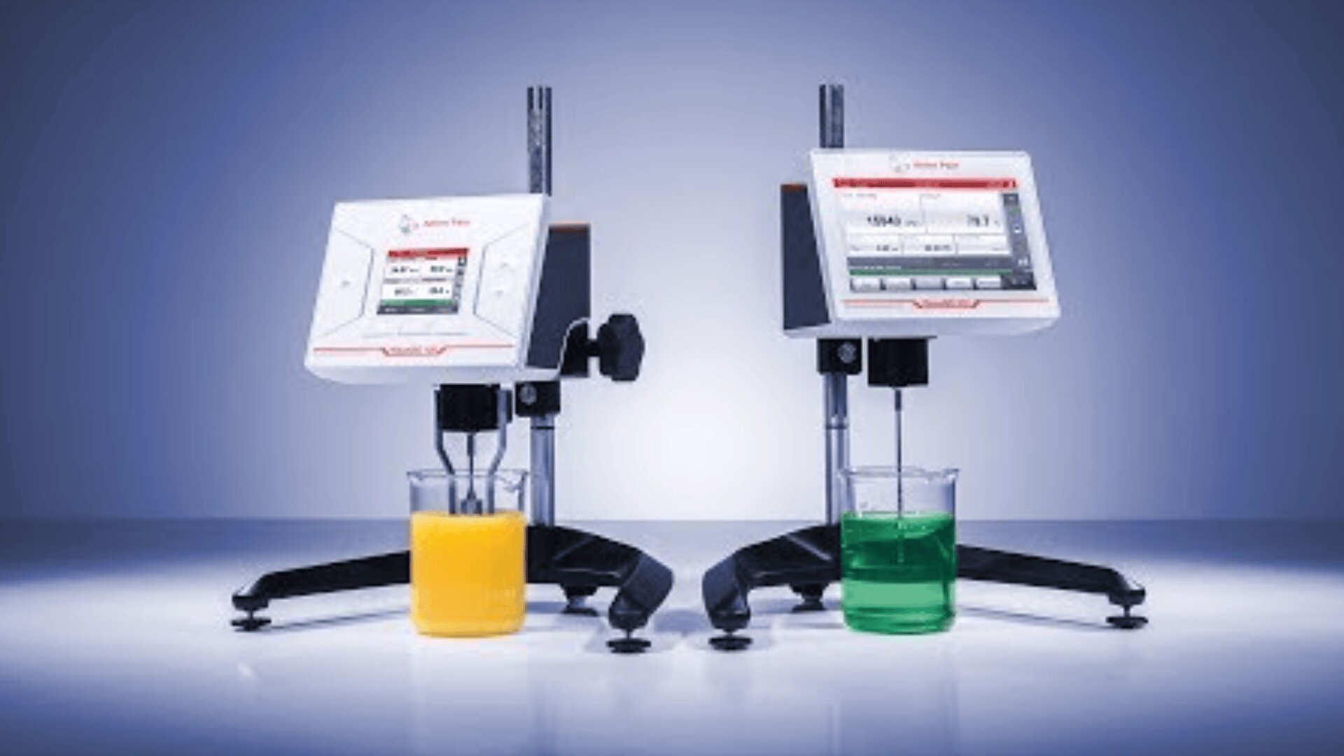 Zwei digitale Labor-Viskosimeter mit Bildschirmen zeigen die Messwerte an, während sie die Viskosität gelber und grüner Flüssigkeiten in separaten Bechergläsern vor einem blauen Hintergrund mit Farbverlauf messen.