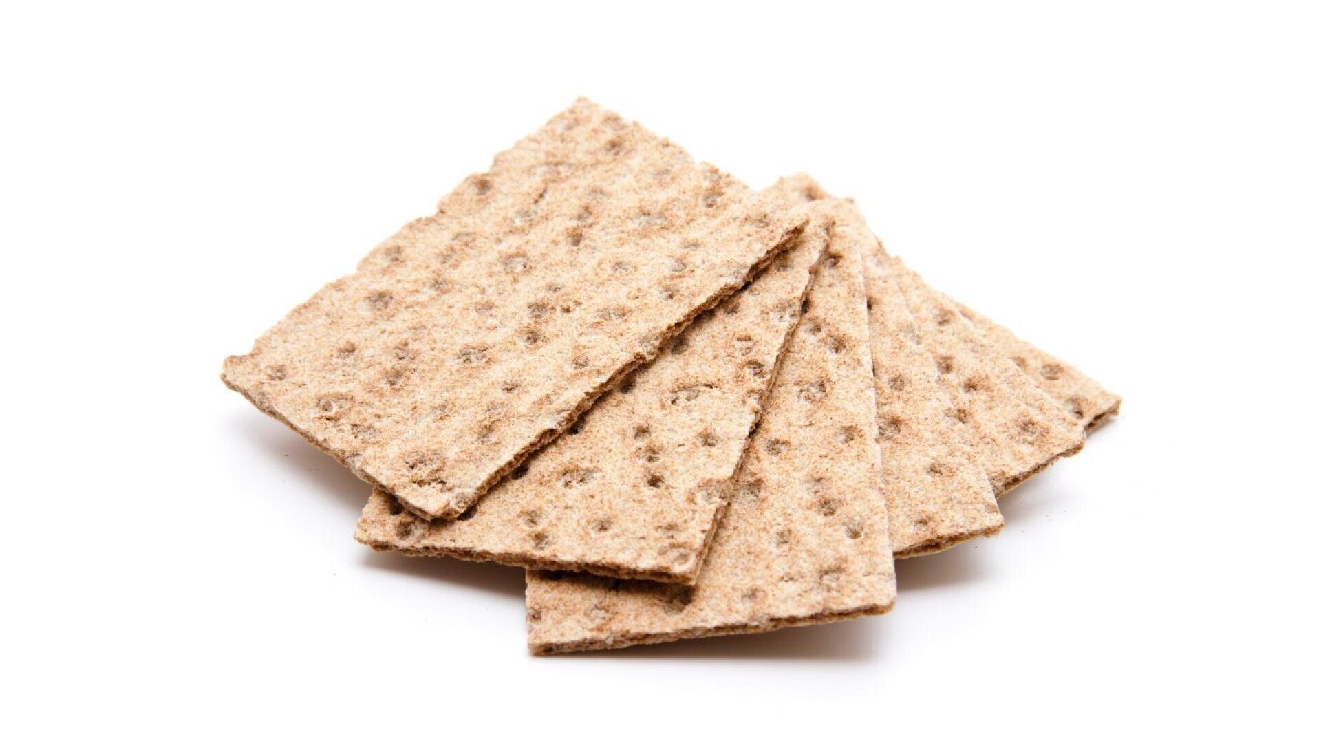 Four rectangular crispbread crackers are arranged in a fanned-out pattern on a white background. The crackers are light brown and have a rough, textured surface with small round holes.