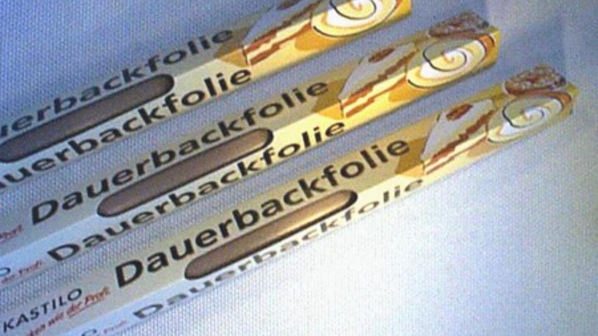 Drei rechteckige Schachteln mit der Aufschrift Dauerbackfolie sind diagonal auf einer weißen Fläche angeordnet. Auf der Verpackung sind braune und gelbe Grafiken zu sehen, die darauf hinweisen, dass es sich um wiederverwendbare Backfolien handelt.