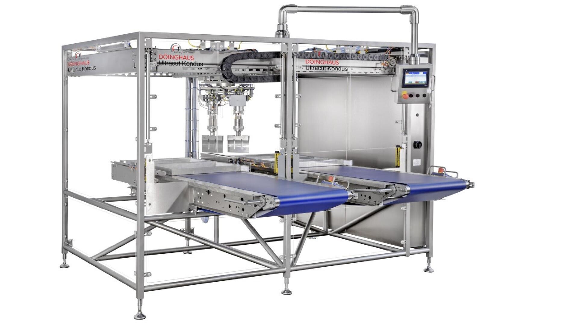 A large industrial food processing machine with metal framework, two blue conveyor belts, piping, and a control panel with a screen, designed for automated handling and sorting of products.
