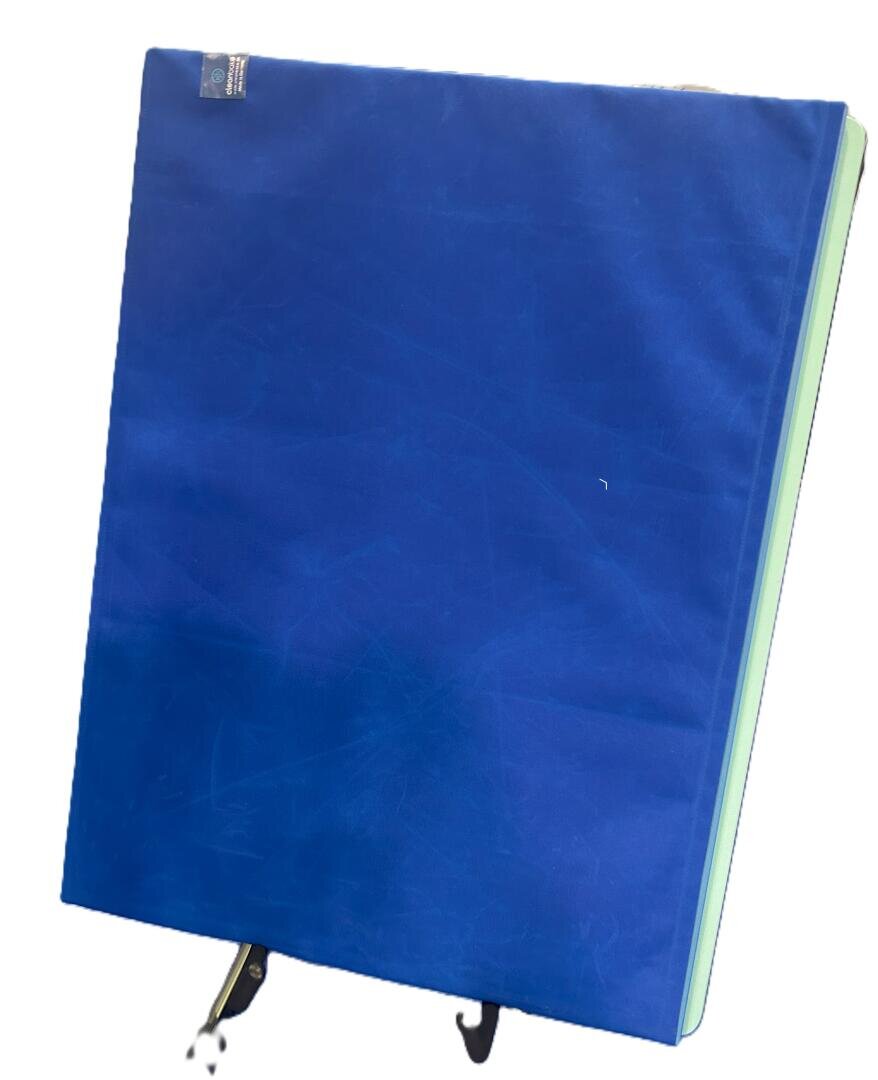 Ein großer rechteckiger Gegenstand, der mit einem leuchtend blauen Stoff überzogen ist, mit Haken an der Unterseite, der sich schräg neigt.