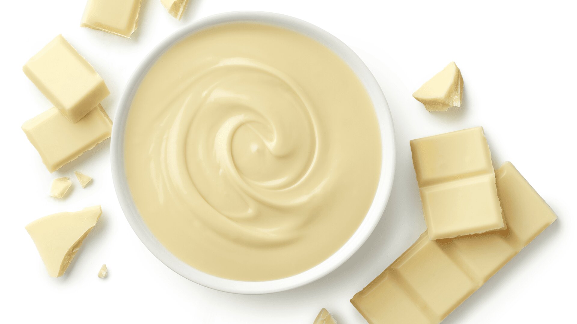 A white bowl filled with creamy white chocolate spread is surrounded by broken pieces of white chocolate bars on a white surface.