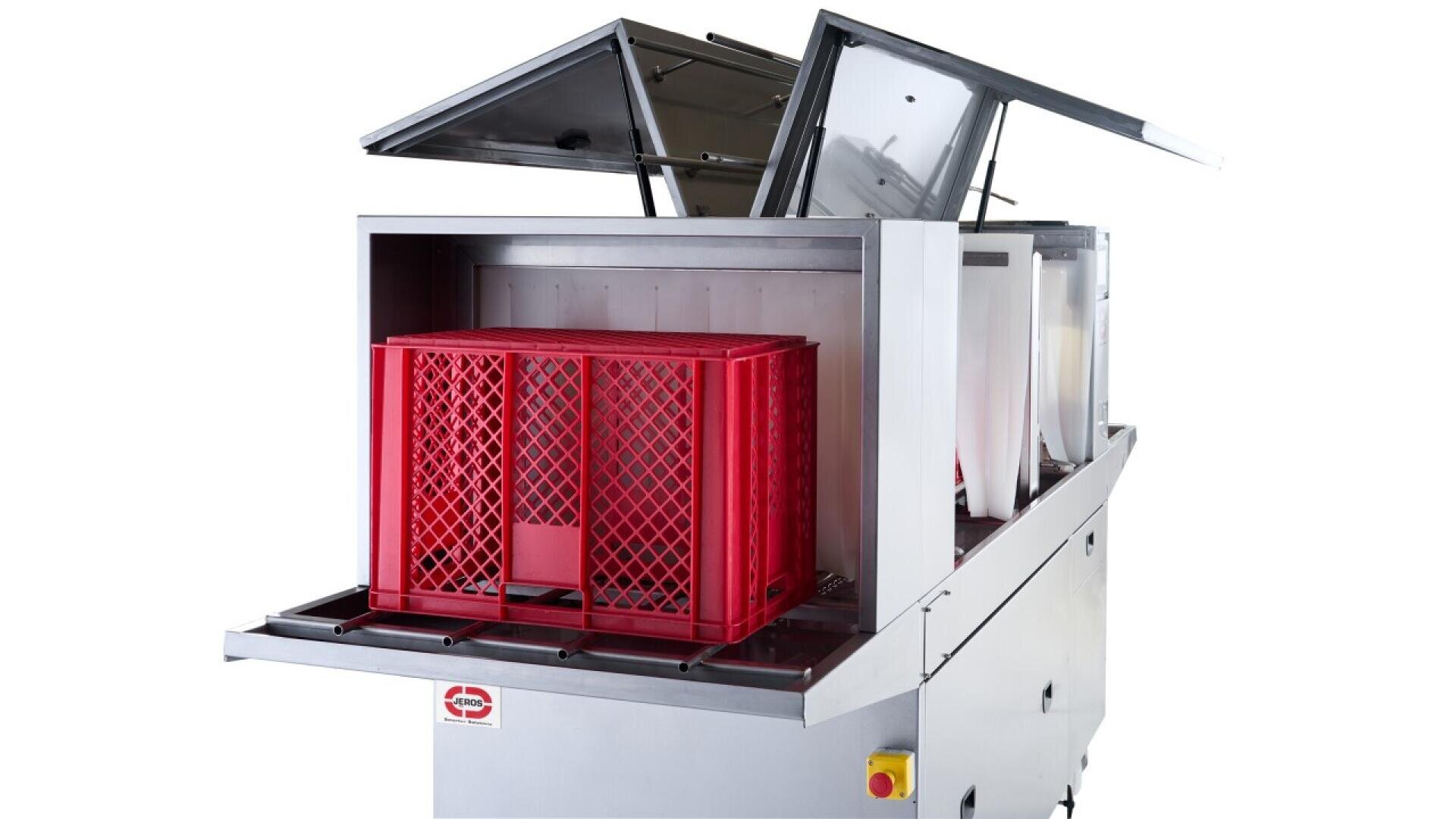A commercial dishwasher with its lids open, holding a large red plastic crate inside, ready for washing. The machine is silver, with a yellow button on the front and a plain white background.