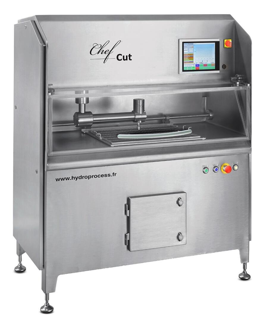 A stainless steel industrial food cutting machine labeled Chef Cut with a touchscreen control panel, emergency stop button, and multiple control knobs, standing on adjustable legs.