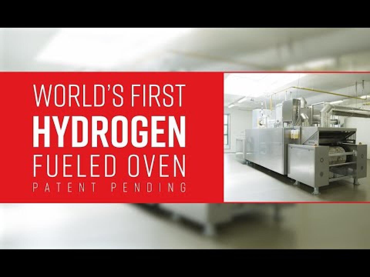 A large industrial oven in a bright room next to a red banner that reads Worlds First Hydrogen Fueled Oven Patent Pending.