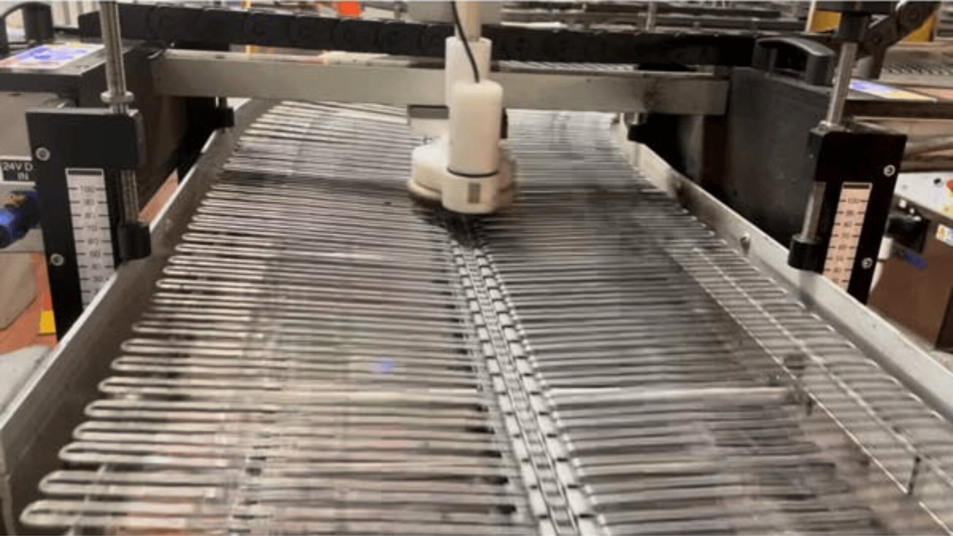 Eine Fabrikmaschine ordnet Reihen von Reagenzgläsern auf einem Metallband an und bereitet sie für die nächste Stufe der Verarbeitung oder Verpackung in einer industriellen Umgebung vor.