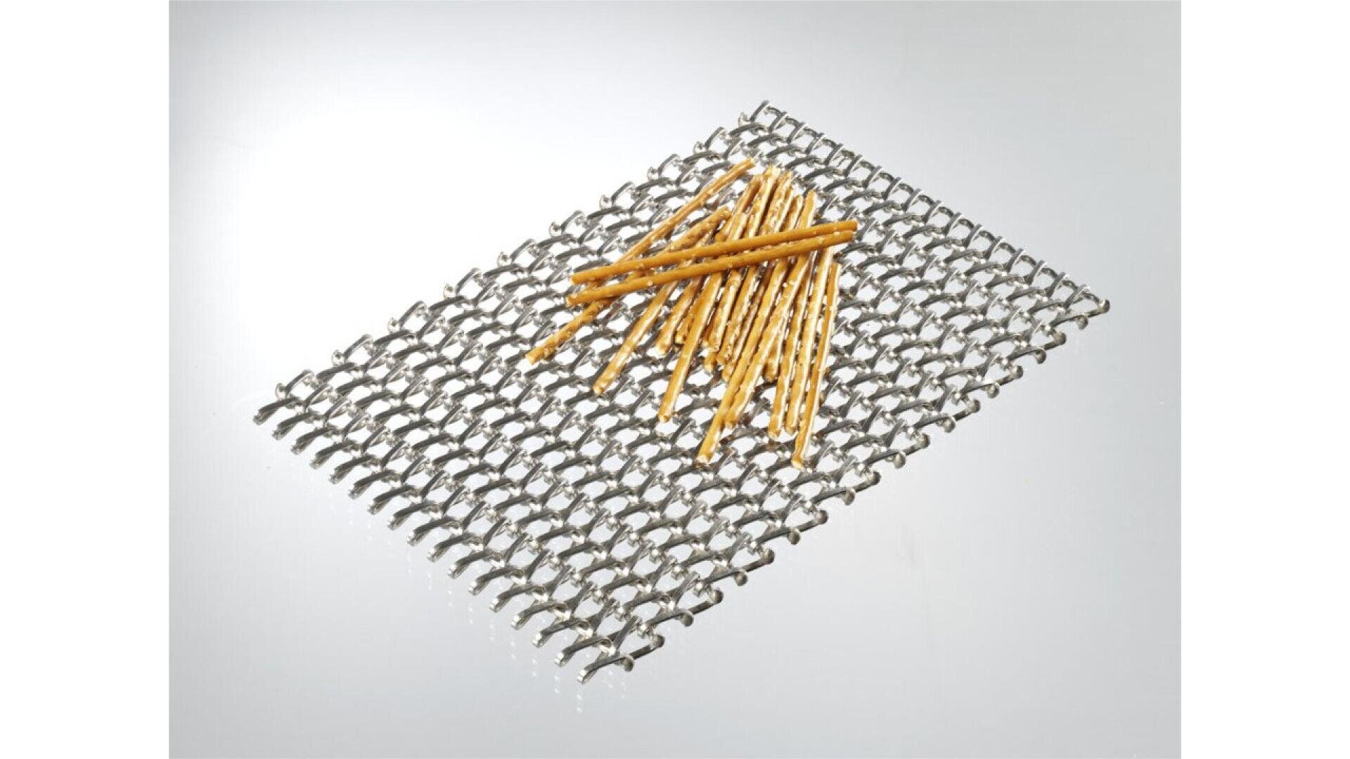 A group of pretzel sticks is arranged on top of a rectangular metal wire mesh, set against a plain white background.