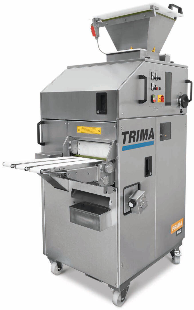 Eine große industrielle Brotteigtrenn- und Abrundungsmaschine von Trima mit einem Metallgehäuse, einem Bedienfeld, einem Trichter auf der Oberseite, einem Förderband und Rädern für die Mobilität.