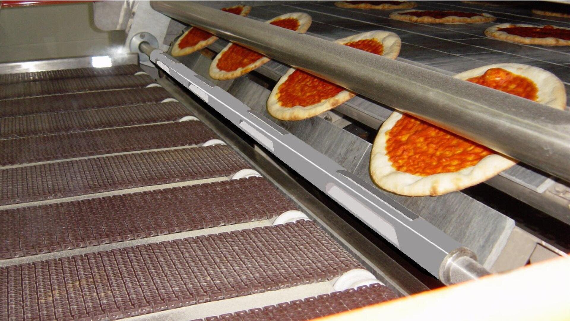 Teilweise gebackene Pizzen mit Tomatensoße laufen über ein Förderband in einer kommerziellen Produktionsmaschine, wahrscheinlich in einem Lebensmittelverarbeitungsbetrieb.