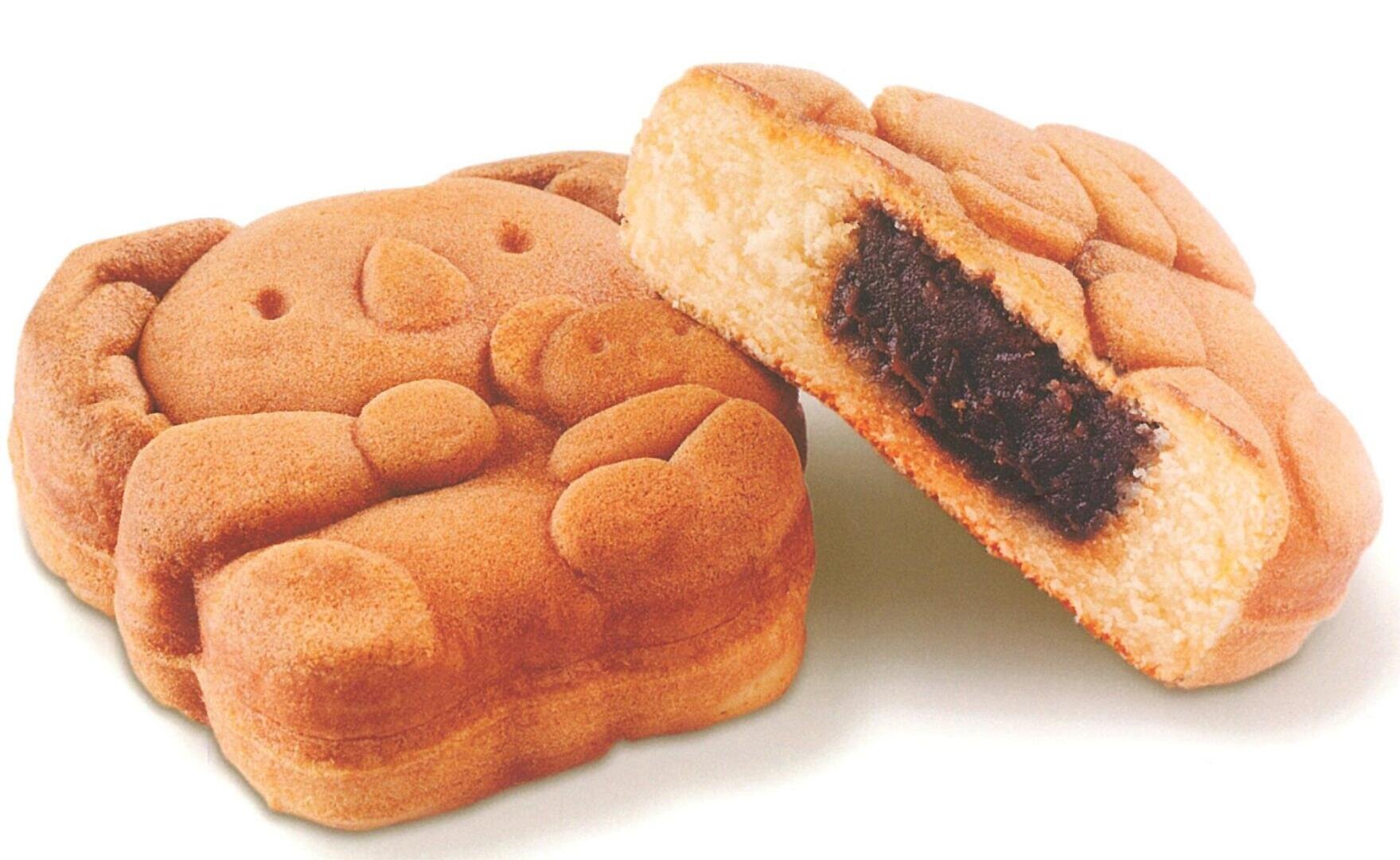 Zwei Gebäckstücke in Form von Koalas, ein ganzes und ein halbiertes, das eine dunkle, süße Füllung enthält, vor einem weißen Hintergrund.