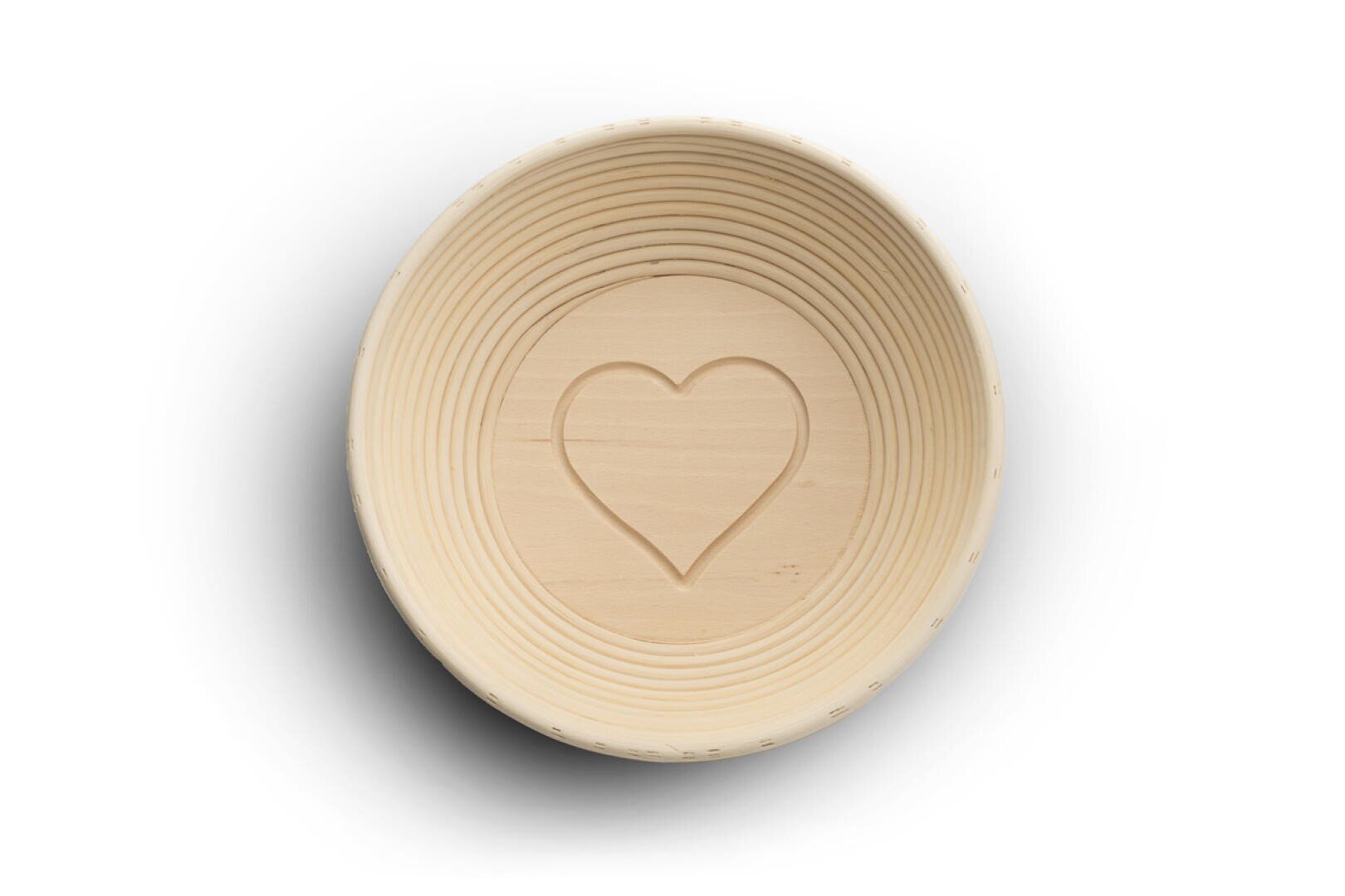 Eine runde, helle Holzschale mit einer geschnitzten Herzform in der Mitte, von oben betrachtet, vor einem weißen Hintergrund.