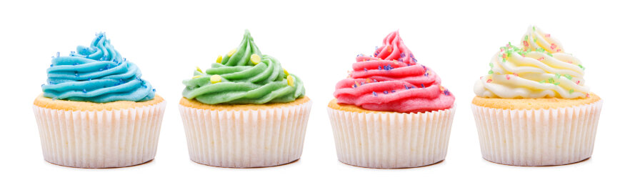Four cupcakes in a row with colorful frosting: blue, green, pink, and white, each topped with sprinkles, against a white background.