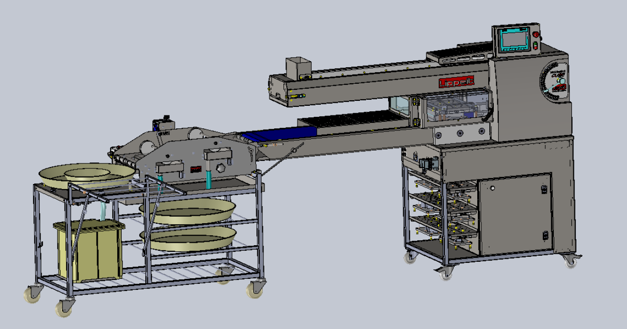Industrial food processing machine with digital controls, conveyor belt, and stainless steel racks on wheels. Nearby is a metal cart holding large round trays and rectangular containers.